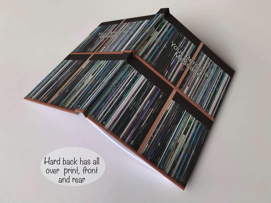 a hardback notebook open and placed down on a surface, the image on the front and back is that of vinyl records stacked along a shelf, with a personal message