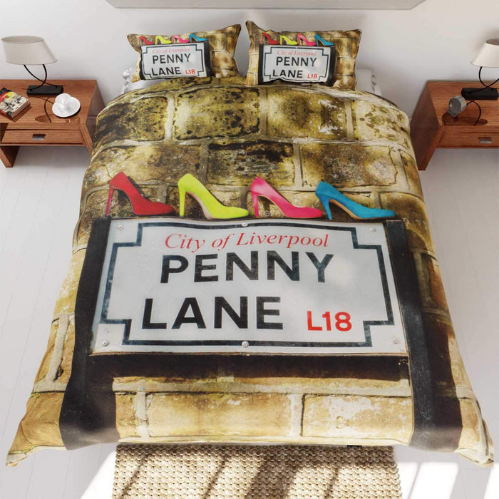 a duvet on a bed, the duvet having a picture of the penny lane road sign in liverpool with 4 coloured high heel shoes on top of the sign