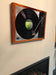 A canvas print hung on a chimney breast in a living room above a lit fire, the canvas shows an image of a vinyl record player with a record playing