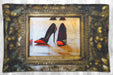 A blanket flat on the floor, the blanket having an image of a pair of black and orange high heel shoes reflected in a brass mirror