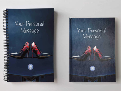 Two notebooks, side by side, both having covers with an image of a pair of dark blue ladies high heel shoes laid flat on the bonnet or hood of a high performance car, with a personal message on the cover