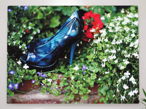 a pair of blue shoes sat in a flower bed, with green leaves and white flowers