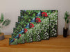 multiple sizes of a canvas print, each print having a pair of blue shoes sat in a flower bed, with green leaves and white flowers, all leaning against each other on a wooden floor
