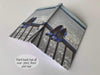 An open hardback notebook having a cover with an image of a pair of shoes hung on a railing in front of an ocean, with a personal message on the cover