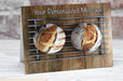 a birthday or greetings card on a desk with an envelope and pen, the card having an image of two sourdough loaves of bread adjacent to each other resting on a metal rack in a top down landscape viewpoint