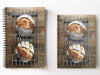 a pair of notebooks, one spiral bound, one hard back, next to each with image of two large sourdough loaves sat on a wire rack upon a table and seen from overhead