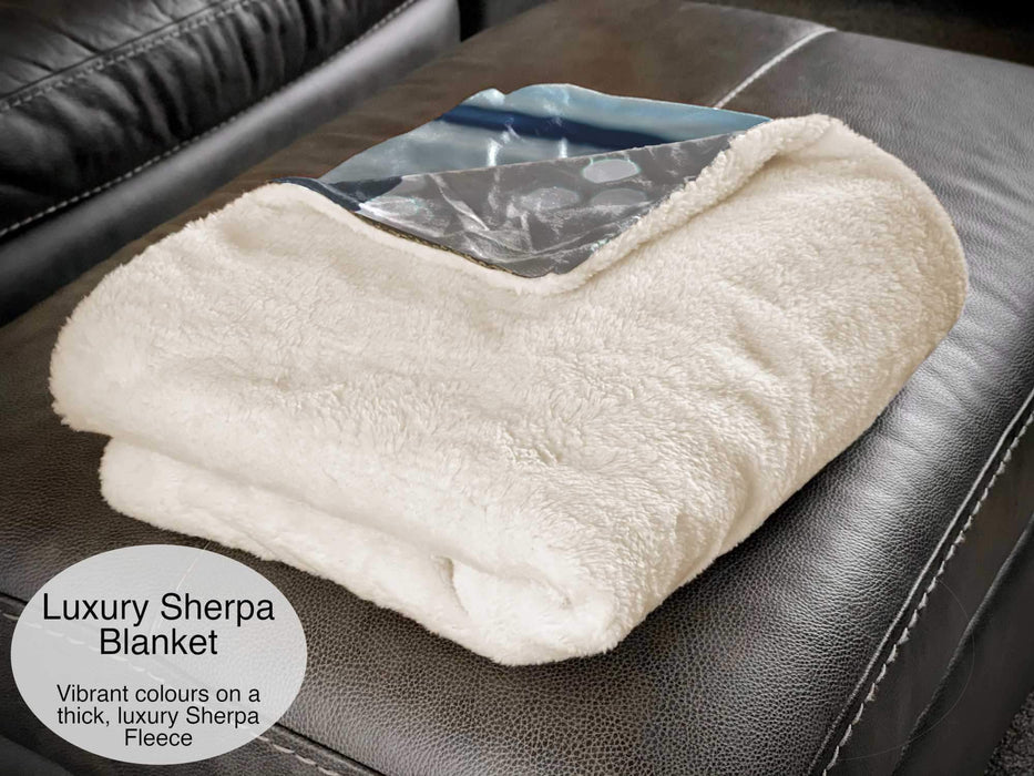 A white sherpa blanket folded over and sat on a couch