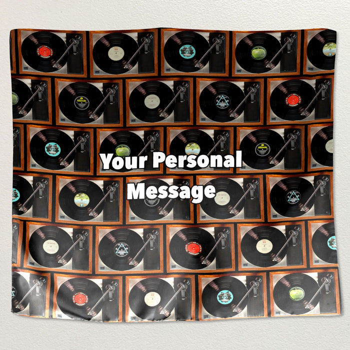 A montage of record players printed on a tapestry wall hanging fabric, each record player with different vinyl records, along with a personal message, the tapestry hung on a white wall