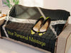 A blanket drapped over a couch, the blanket having an image of a pair of yellow high heel shoes hung on the net of a tennis court, along with a printed personal message