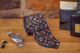 a partially rolled neck tie showing a montage of record players on the tie, sited on a bed side table