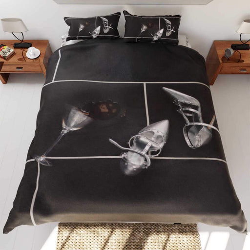 a duvet cover on a bed, the duvet having an image of a spilt cocktail on a kitchen floor along side a pair of silver high heel shoes