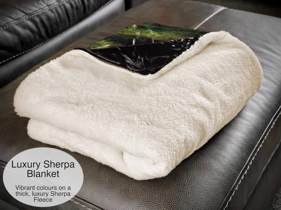 a blanket folded showing white fleece with a corner folded back showing black and green colours